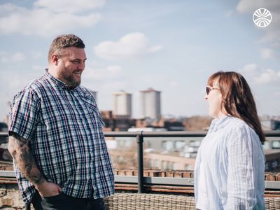 Two team members engaged in conversation on a rooftop terrace overlooking urban cityscape.