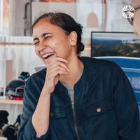 South Asian woman in casual attire laughing in an office setting.