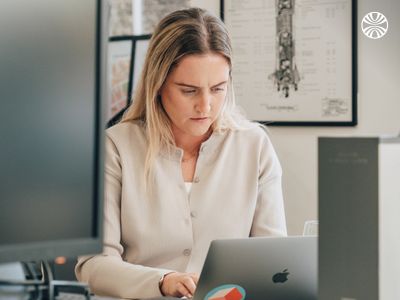 White woman focused on her laptop, sitting alone in the office.