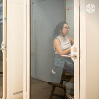 A person sitting it a glass-fronted private booth, which offers a quiet area for focused work or calls.