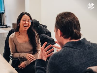 Two colleagues sharing an animated and cheerful conversation in an office break area, captured during a moment of laughter.