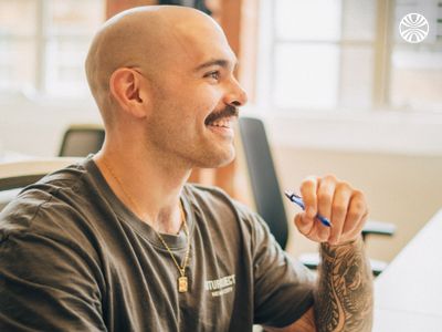 Man with tattoos smiling in a discussion.