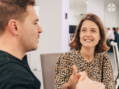 Two colleagues having an engaging conversation in a minimalist meeting space with natural light.