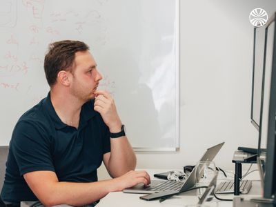 White man seated with a laptop, focused on work.