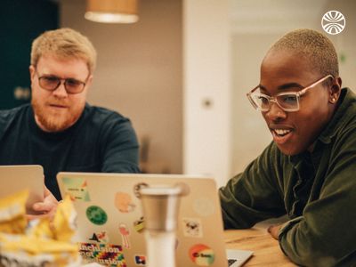 Black woman and white man working together on laptops.