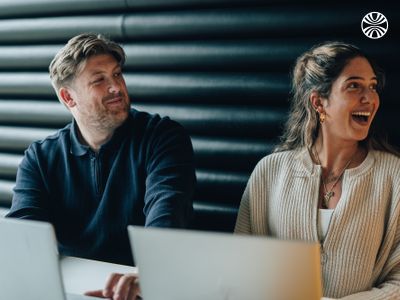 2 people smiling during a team meeting, engaged in animated discussion.