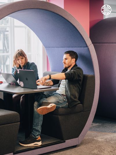 Two colleagues collaborating in a circular booth alcove, creating a cozy meeting space.