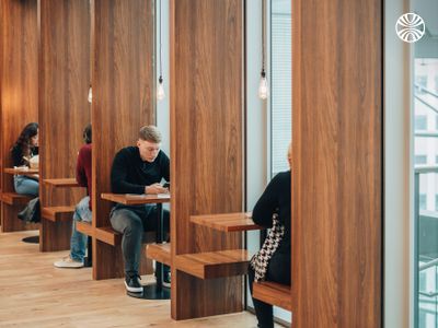 Private wooden work booths with built-in desks provide focused individual workspace areas in modern office setting.