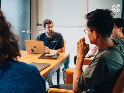 Small team of white and Asian colleagues in a meeting, laptops open.