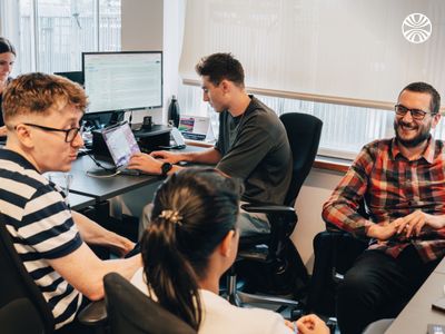 Group of colleagues discussing amd smiling in a collaborative workspace.