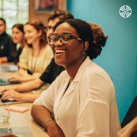 Black woman smiling in a meeting with colleagues.