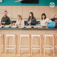 Four colleagues serving themselves from dishes on a modern office kitchen counter.