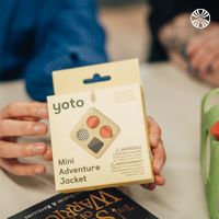 Hands holding a Yoto Mini Adventure Jacket product package during an informal meeting.