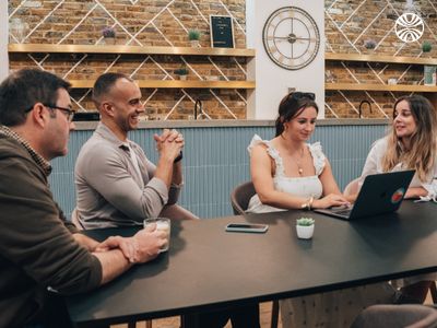 Team members collaborating around a table with laptops during an informal meeting.