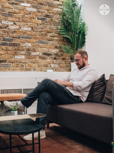 White man relaxing on a couch in a quiet office area.