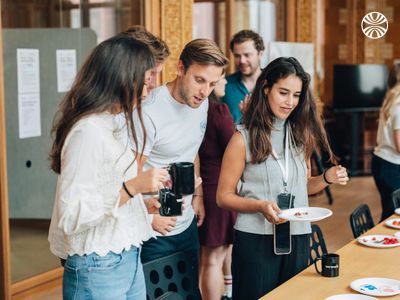 Diverse group of employees chatting over coffee and snacks, appearing relaxed and enjoying a break.