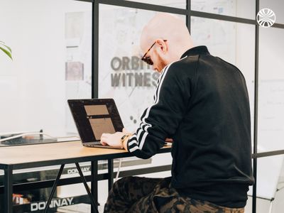 White man working on a laptop at a desk with “Orbital Witness” branding in the background.