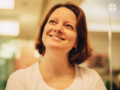 Woman smiling with short hair and hoop earrings.