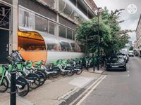 Cycle hire docking station outside a modern, curved glass building.