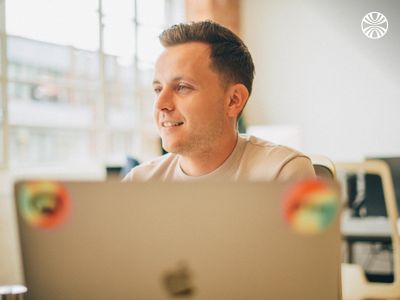 Man smiling while working on a laptop.