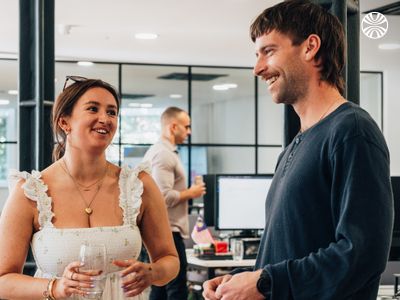 Two white coworkers, discussing something in the office kitchen.