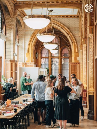 Large office hallway with arched ceilings, where colleagues are gathered around a table with snacks.