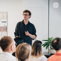 CEO Will Pearce leads the all hands, standing at the front of a minimalist room with plants.