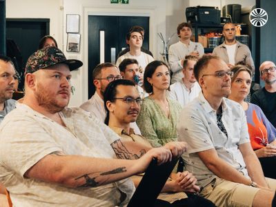 Diverse audience of employees seated in rows, paying attention to a presentation.