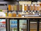 Well-stocked cereal and snack dispensers and jars sit on an island counter. Fridges under the counter are full of drinks, including beers and bottles of wine.