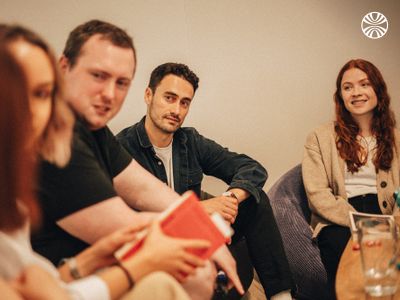 A small group of coworkers in a conversation in a meeting room.