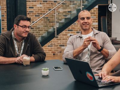 Two colleagues sharing a laugh during a casual conversation at a table.