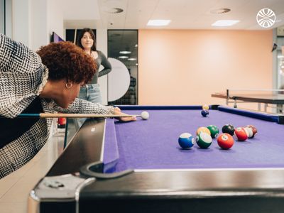 Two colleagues taking a break to play pool in the office recreation area.
