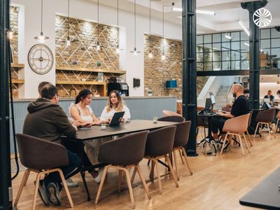 People working and meeting around a table in an open workspace.