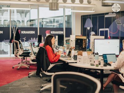 Individual working at a desk in an open office environment with magenta carpet accents.