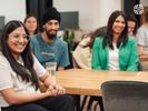 A diverse group of colleagues seated around a table and smiling during company all hands.