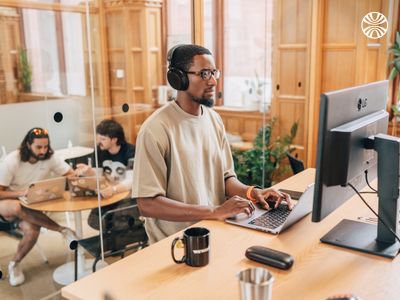 Black man focused on his computer, working with concentration in an office environment.