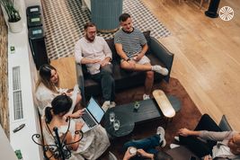 Small group of coworkers sitting on sofas, chatting informally.