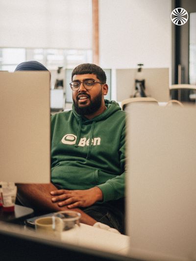 Man in green hoodie working at his desk.