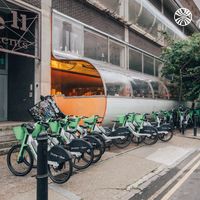 Cycle hire docking station outside a modern, curved glass building.