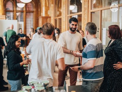 Diverse group of employees standing together, casually chatting near a table with coffee and snacks.