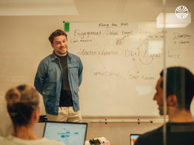 Man presenting in front of a whiteboard with business concepts.