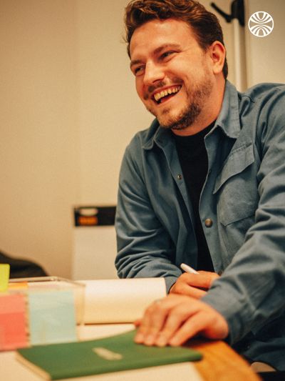 Man laughing while making notes at a table.