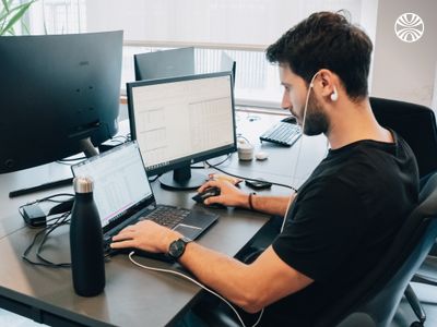 Employee wearing headphones working at a desk with a monitor.