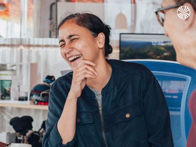 South Asian woman in casual attire laughing in an office setting.