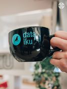 Close-up of a black coffee cup featuring the turquoise Dataiku logo and bird symbol.