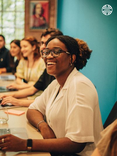 Black woman smiling in a meeting with colleagues.