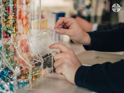 Close-up of hands selecting colorful candy from a dispenser.