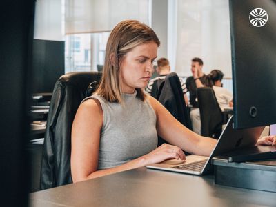 White woman intently working on her laptop at her desk.