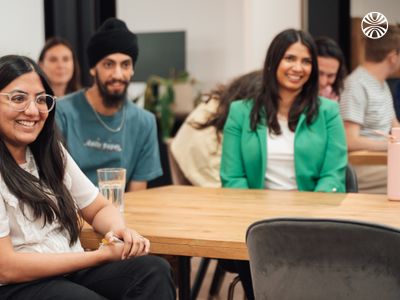 A diverse group of colleagues seated around a table and smiling during company all hands.